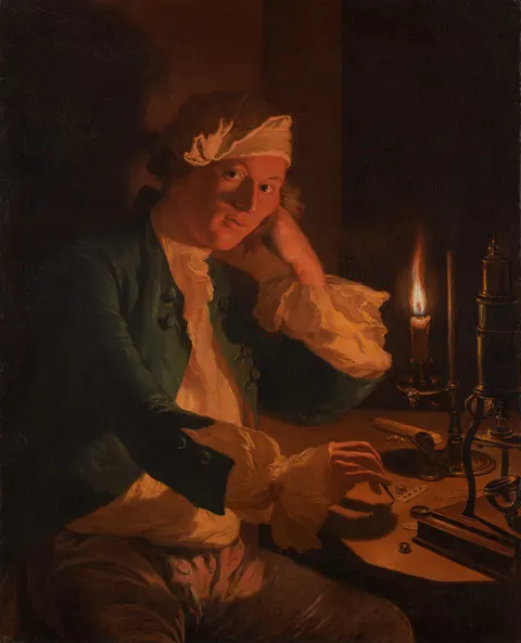 A Scientist Seated at a Desk by Candlelight