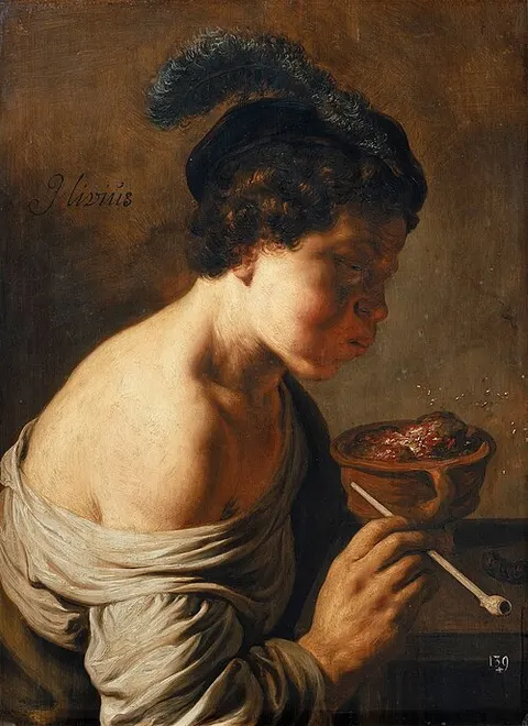 A youth blowing on coals.