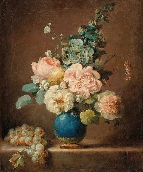 Vase of flowers and grapes on a stone ledge