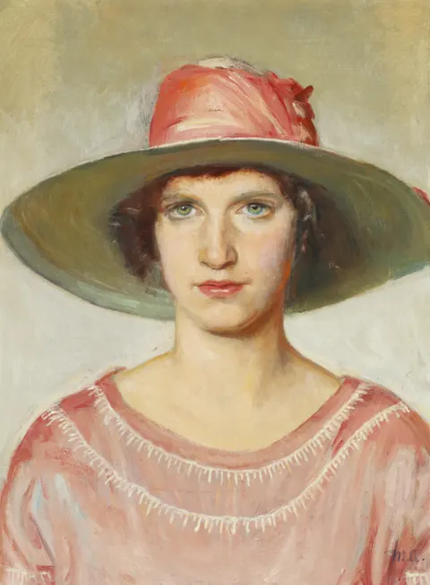 Portrait of a girl in a pink dress and a straw hat with a pink ribbon
